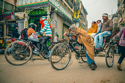 Varanasi, Uttar Pradesh, India - December 26, 2019: Three happy people enjoy their ride on a rickshaw pulled by a poor rickshaw-puller who works hard despite his old age.