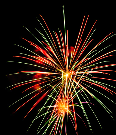 Two bursts of multicolored fireworks, one large one small, with a few puffs of reddish-orange smoke
