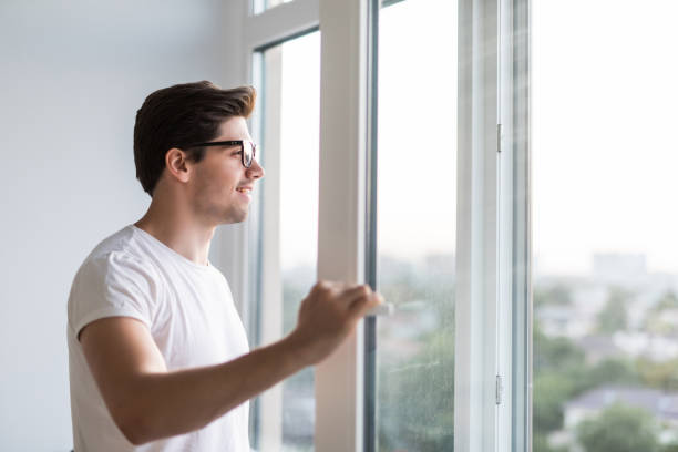 istock Young man opens the window. Ventilating a house in hot weather. 1197917792