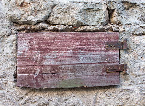 Vintage wooden closed shutter in stone wall