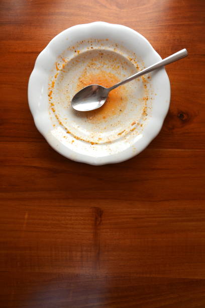 istock Empty white plate with spoon on wooden table, flat lay top view, red leftovers from soup or sauce 1197928208