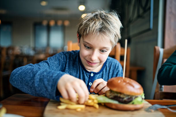 Hungry boy eating burger with fries for lunch Little boy aged 10 enjoying unhealthy food. He is having burgers and fried in restaurant.
Nikon D850 spanish hamburger stock pictures, royalty-free photos & images