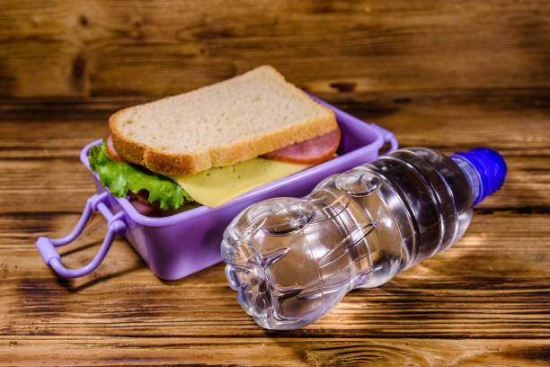 бутылка воды и коробка для завтрака с бутербродами на деревянном столе - lunch box packed lunch school lunch lunch стоковые фото и изображения