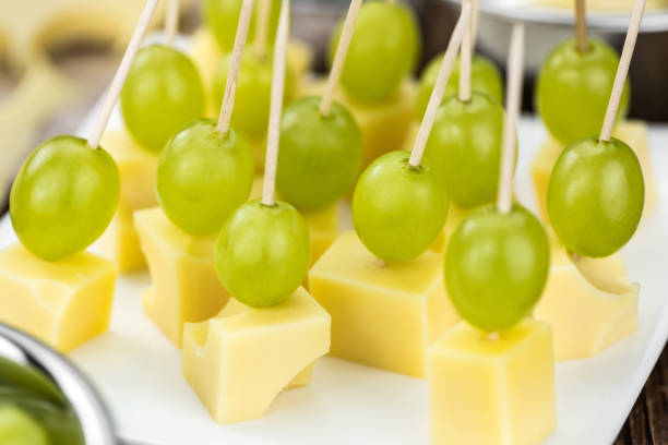 Vintage wooden table with Cheese blocks and grapes as detailed close-up shot (partyfood)