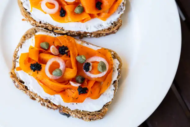 Vegan carrot lox - Vegan Smoked Salmon based on carrots which is served on a healthy sourdough bread topped with onions, capers and vegan algae caviar