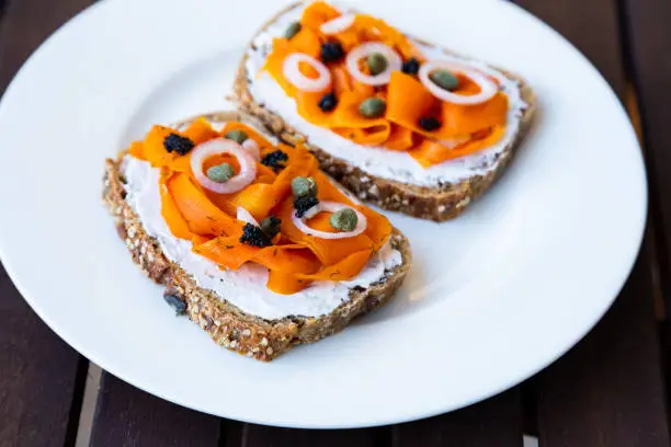 Vegan carrot lox - Vegan Smoked Salmon based on carrots which is served on a healthy sourdough bread topped with onions, capers and vegan algae caviar