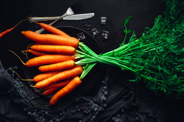 Fresh carrots on a black plate with ice. Food background for recipes and books stock photo