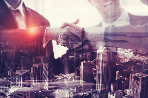 Businessman shaking hands. This is a montage which has a city scape overlaid. Success, vision, architecture; building; development, engineering concept.