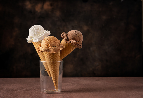 Three sorts of ice creams in cones on dark background