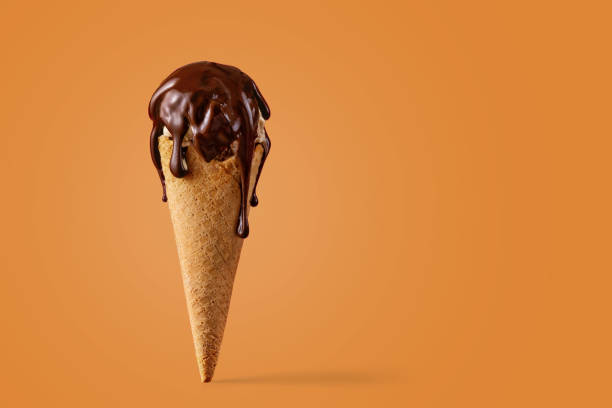 Ice cream cone with chocolate sauce on an orange background. Copy space