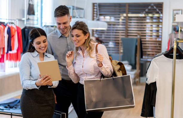 istock Latin american couple evaluating the service at a clothing store on tablet while friendly saleswoman holds it 1197952600