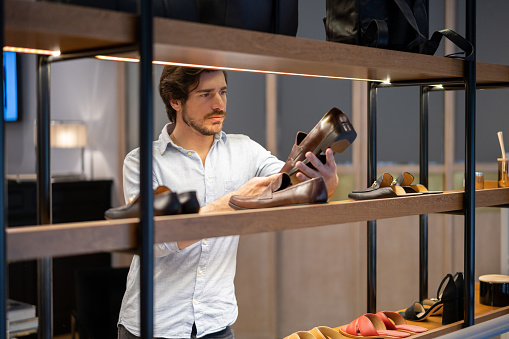 Latin american young man looking at a formal shoe on retail display at a store