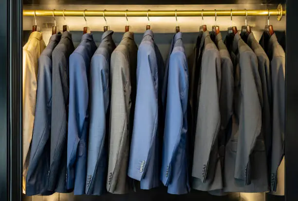 Elegant suits on coat hangers at a men's formal clothing store - Consumerism concepts