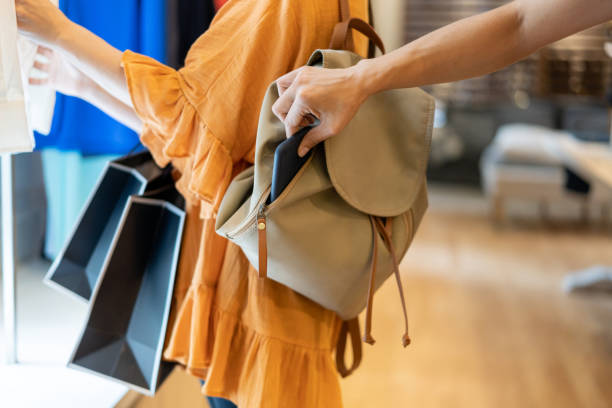 Unrecognizable woman stealing a smartphone from a customers bag at a clothing boutique Unrecognizable woman stealing a smartphone from a customers bag at a clothing boutique - close up shot pickpocketing stock pictures, royalty-free photos & images