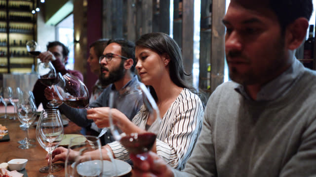 Group of young couples at a wine tasting class learning and moving the wine while looking at it’s texture