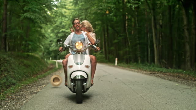 SUPER SLO MO Couple having fun riding a scooter through a forest