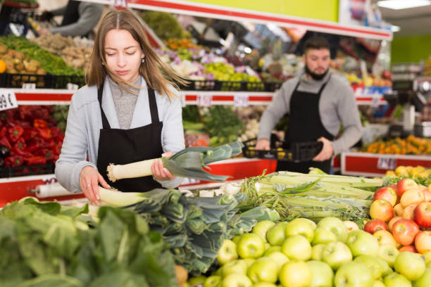 istock Shopping assistant puts leek on supermarket counter 1197954953