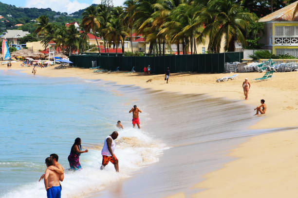 People on the beach, Rodney Bay, St. Lucia. View of beach and water, resort buildings in background.