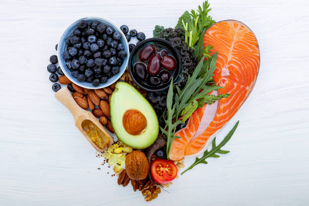 Heart shape of ketogenic low carbs diet concept. Ingredients for healthy foods selection on white wooden background. Balanced healthy ingredients of unsaturated fats for the heart and blood vessels. Heart shape of ketogenic low carbs diet concept. Ingredients for healthy foods selection on white wooden background. Balanced healthy ingredients of unsaturated fats for the heart and blood vessels. heart health stock pictures, royalty-free photos & images