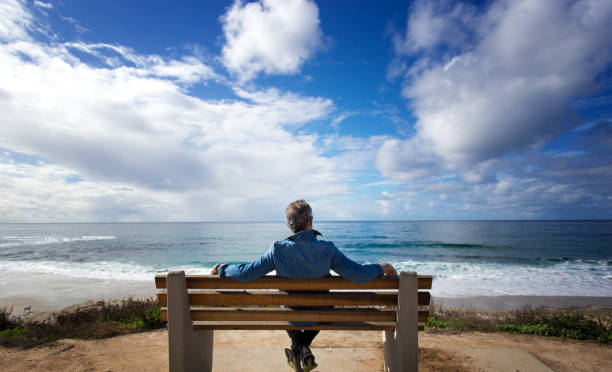 La Jolla, CA: Man Sitting on Bench Looking at Pacific Ocean stock photo