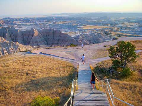 Visitors wander a walkway leading to a panoramic vista of the eroded hills of Badlands National Park in South Dakota.