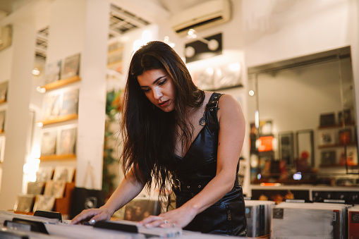 Young woman looking through records at a vinyl shop, Buenos Aires, Argentina.