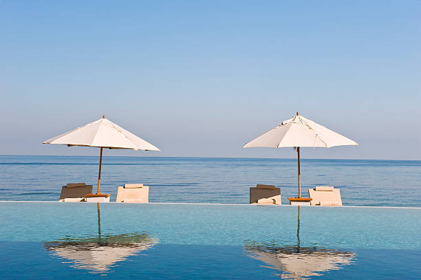 Deck chair and umbrella next to infinity pool stock photo