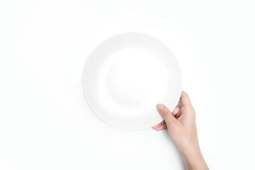 Close-up, holding a white plate on a white background. Isolated background.