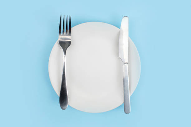 istock A white plate with a spoon on a blue background. Top view. 1197976342
