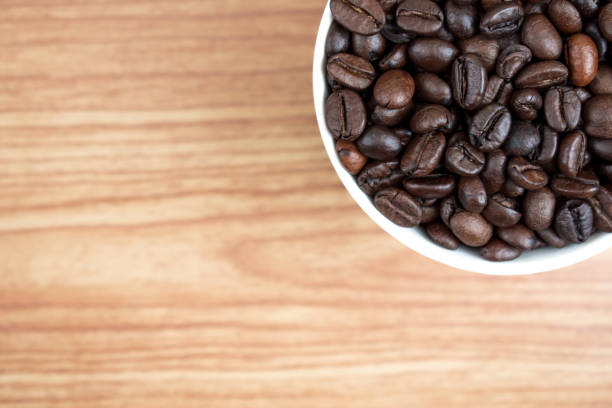istock Coffee beans in a white mug on an old brown wood texture background. With copy space. 1197976438