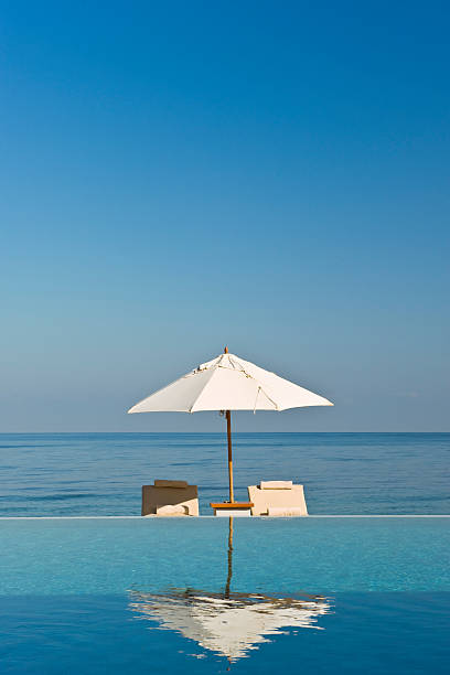 istock Deck chair and umbrella next to infinity pool 119797669
