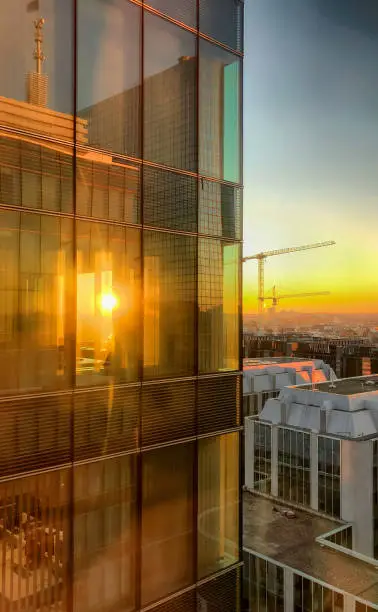 Sunset over the business district of a city where the setting sun shines through the windows of an office building
