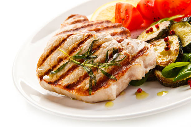 istock Grilled pork steak with vegetables on white background 1197983286