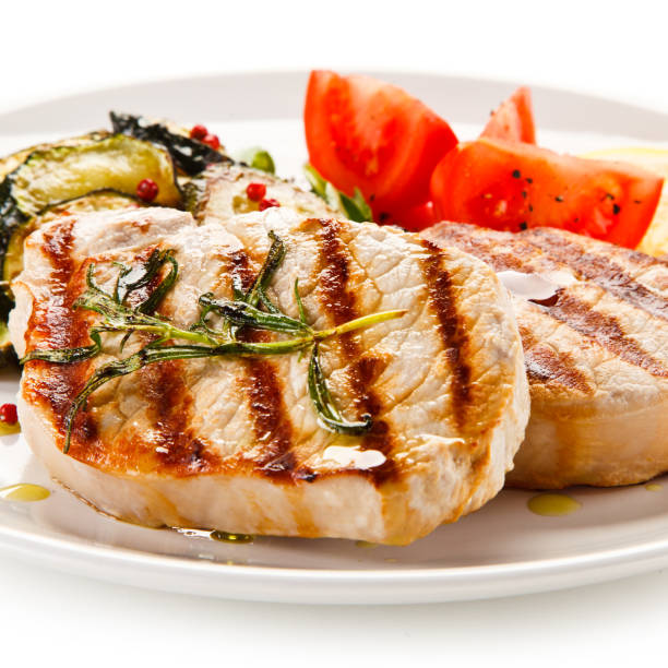 istock Grilled pork steak with vegetables on white background 1197983294