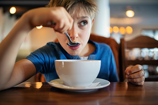 Portrait of little boy wearing blue t-shirt eating soup.
Nikon D850