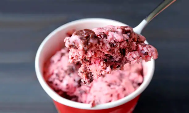 Photo of Closeup a spoon scooping delectable strawberry chocolate chunk ice cream