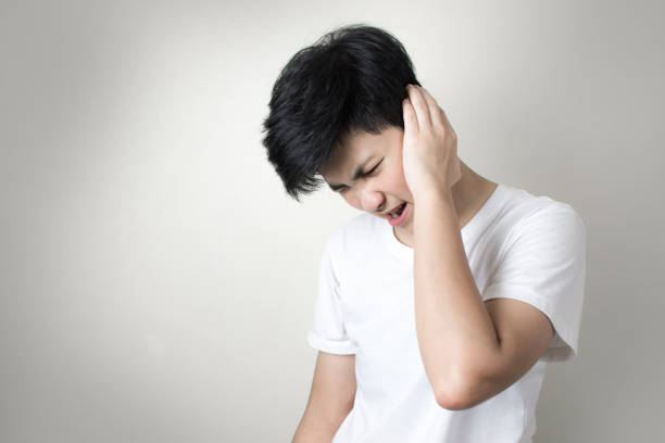 Asian girl with earache that hurts her head isolated on gray background. Asian girl with earache that hurts her head isolated on gray background. neuralgia stock pictures, royalty-free photos & images