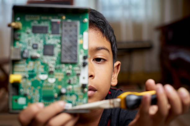 Smart Asian Boy working on Electronic Circuitry at home stock photo