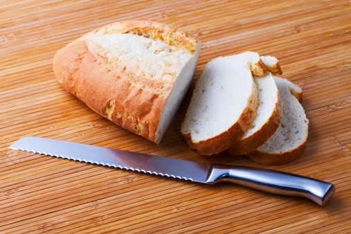 A loaf of irish wheaten bread on white background. The bread is sliced with a knife.