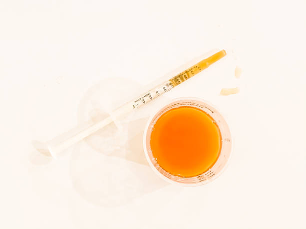 measuring cup of liquid cough or cold syrup medicine and syringe - cough medicine spoon medicine tablespoon imagens e fotografias de stock