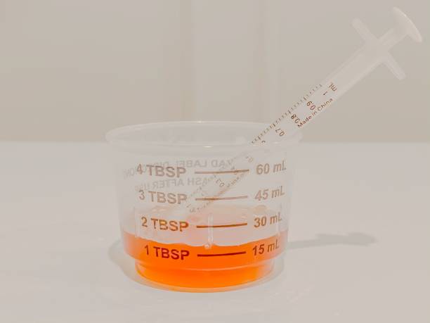 measuring cup of liquid cough or cold syrup medicine and syringe - cough medicine spoon medicine tablespoon imagens e fotografias de stock