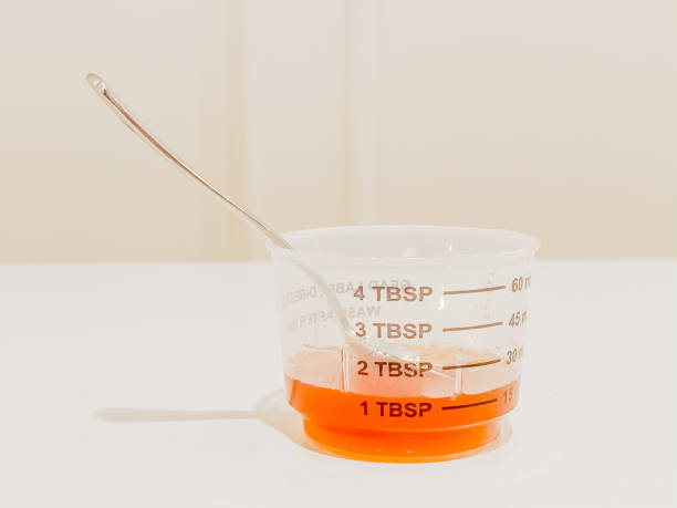 액체 기침 또는 차가운 시럽 약 및 실버 숟가락의 측정 컵 - cough medicine spoon medicine tablespoon 뉴스 사진 이미지