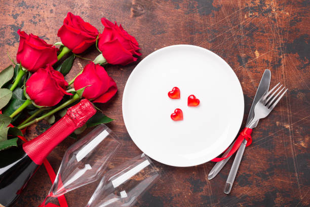 istock Valentines day table setting empty plate, red roses and champagne glasses on wooden background. Top view. Valentine's greeting card 1197998317