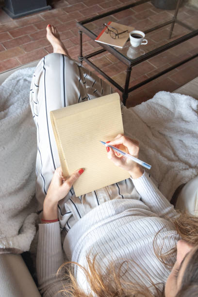 istock Young woman starting to write in a notebook on the sofa at home. 1198003076