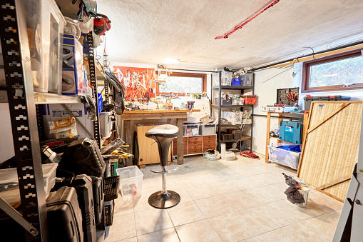 Basement room / workshop in a Scandinavian housing cellar in Copenhagen, Denmark. There are no people in the picture and it is day.\nThe room is full of tools and red stuff in stock. storage