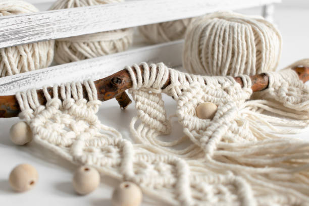 Handmade macrame braiding and cotton threads on rustic wooden stick. Boho image good for macrame and rustic handicrafts banners and advertisement