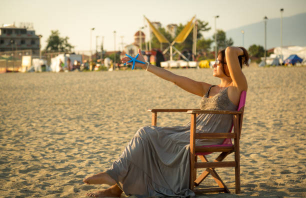 A happy woman sitting on the beach and enjoying sunrise