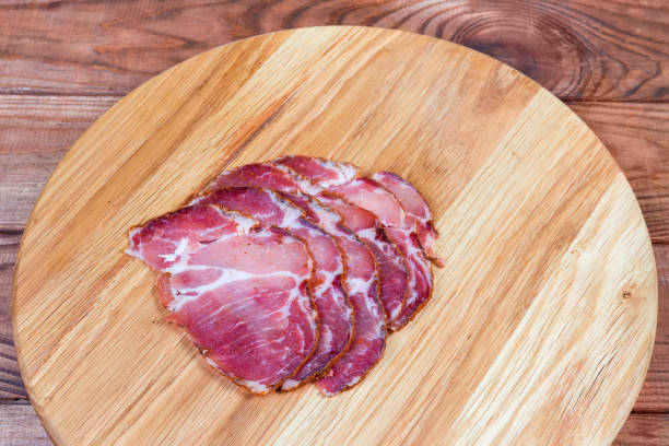 istock Cured pork slices on wooden cutting board on rustic table 1198014643