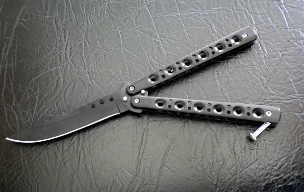 istock Butterfly knife black against black leather close-up. 1198018967