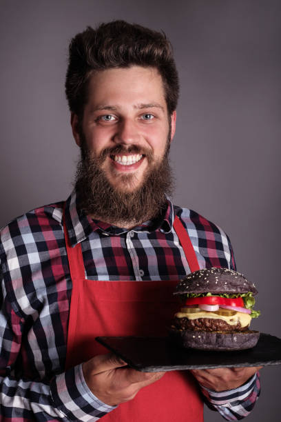 istock Male cook hold black burger 1198023247